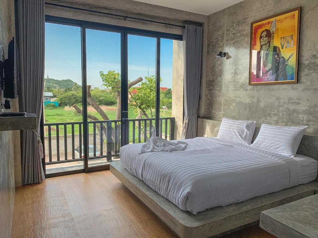 a bedroom with a bed and a large window at Bosston Hotel in Phetchaburi