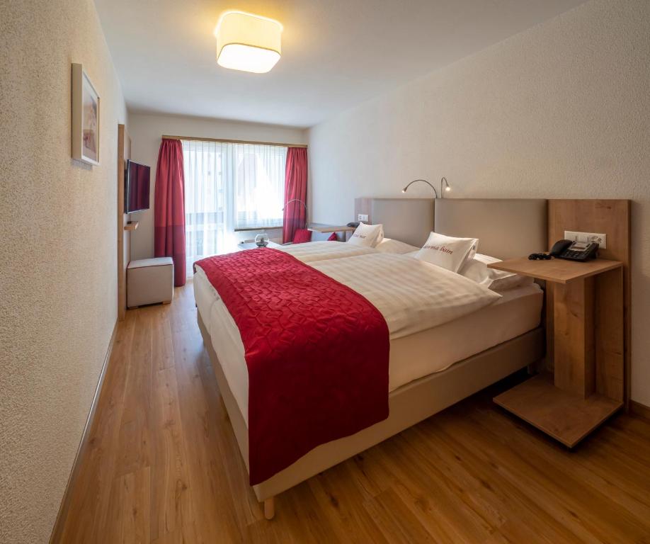a bedroom with a large bed with a red blanket at Hotel Sonne St. Moritz 3* Superior in St. Moritz