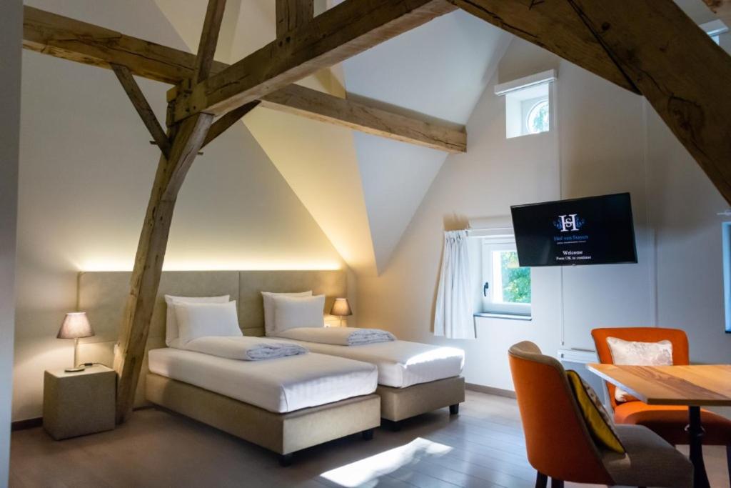 a bedroom with two beds and a table and a tv at Hof van Stayen in Sint-Truiden