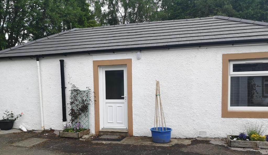 a white house with a door and a window at Arrochoile Cottage in Glasgow