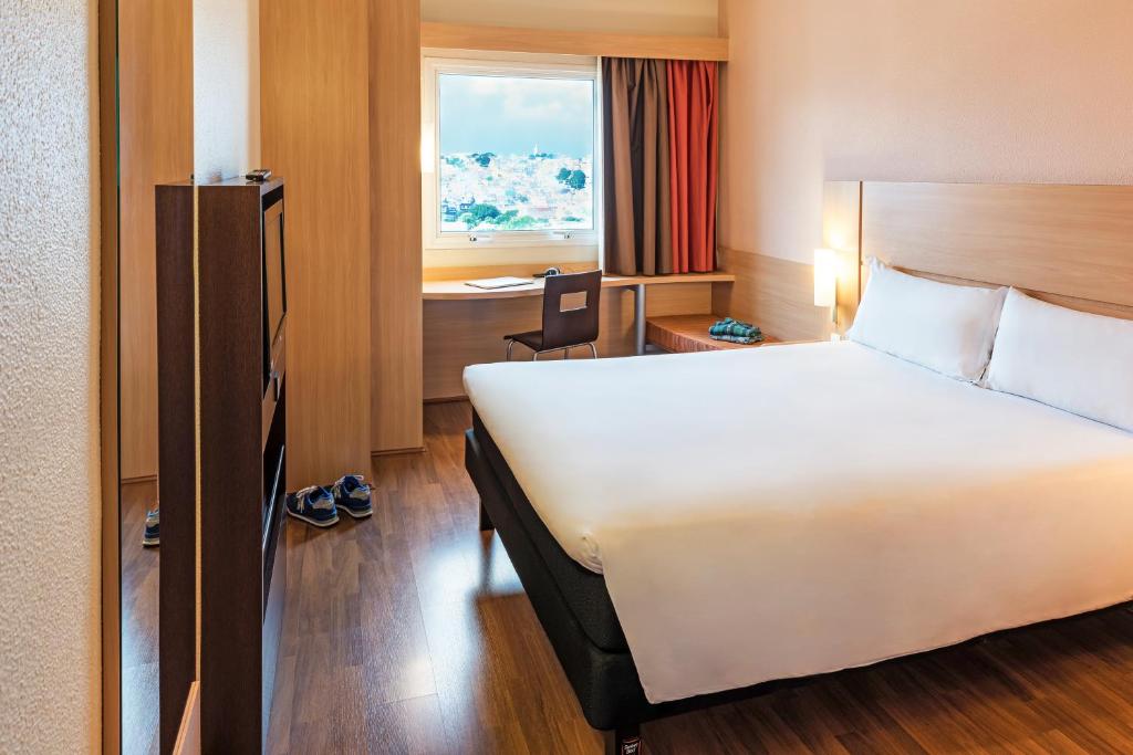 um quarto de hotel com uma cama, uma secretária e uma janela em ibis Sao Paulo Interlagos em São Paulo