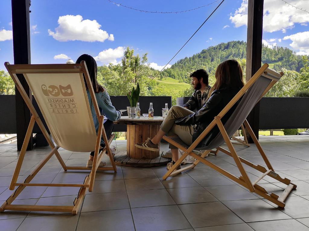 um grupo de pessoas sentadas numa mesa em cadeiras em Hostel Idrija em Idrija