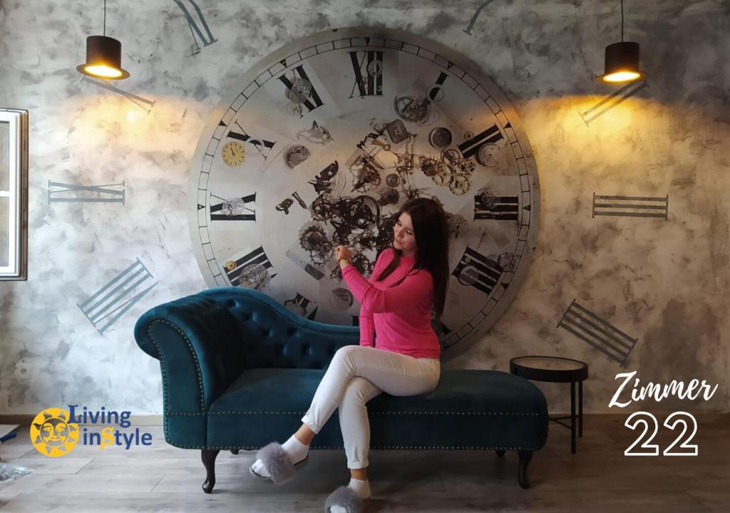 une femme assise sur un canapé devant une horloge dans l'établissement Living inStyle, à Krems an der Donau