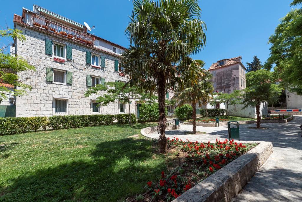 a building with a palm tree and flowers in a park at Palazzo D Apartments in Split