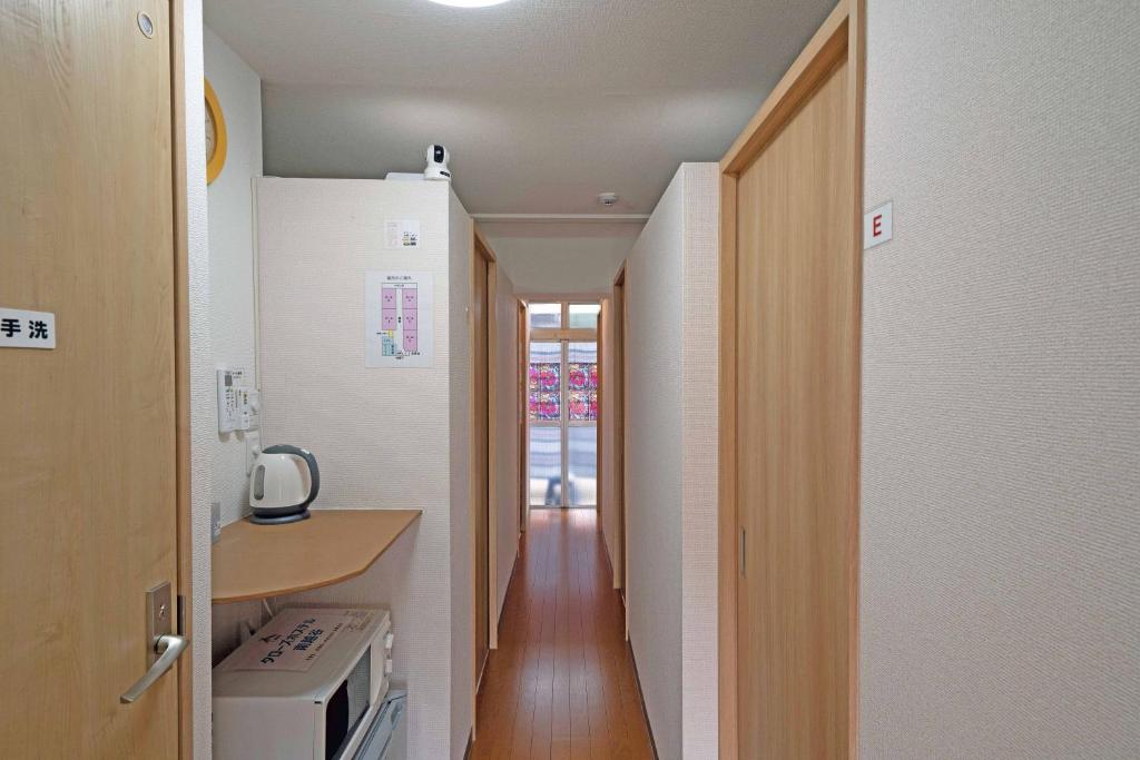 pasillo que conduce a una cocina con encimera y fogones en Taro's Hostel Minami Koshigaya, en Koshigaya