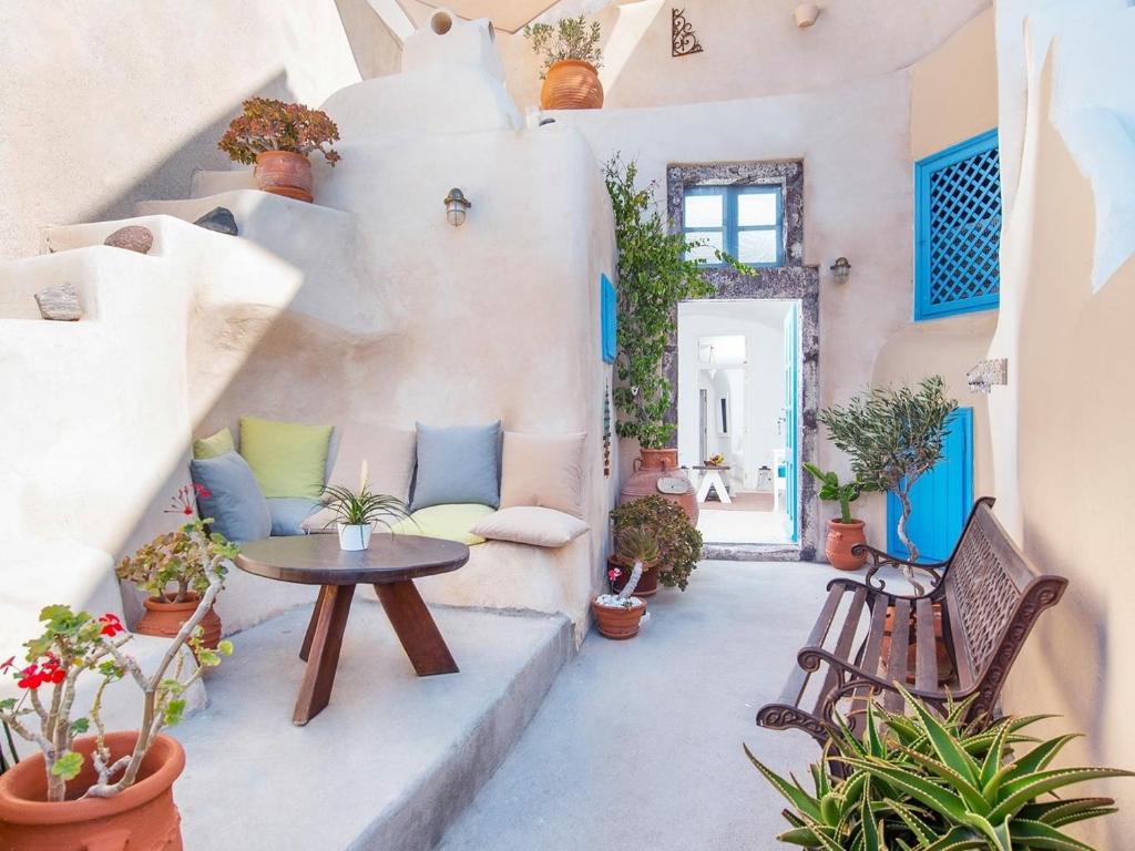 une cour avec une table, des chaises et des plantes dans l'établissement Anemi House & Villas, à Oia