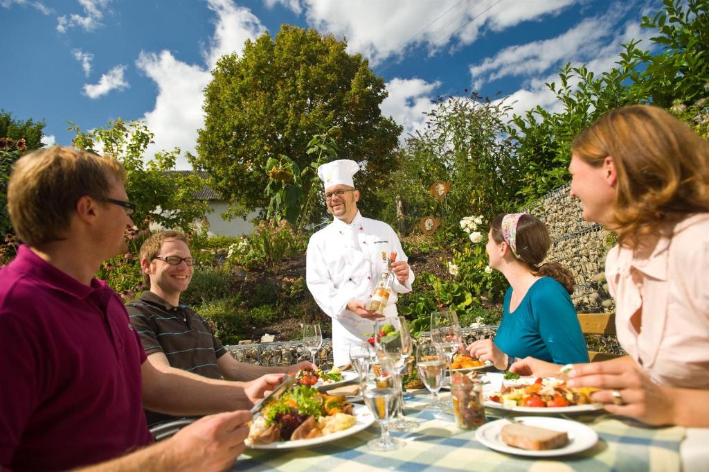 un grupo de personas sentadas alrededor de una mesa con un chef en Gasthaus Herrig, en Meckel