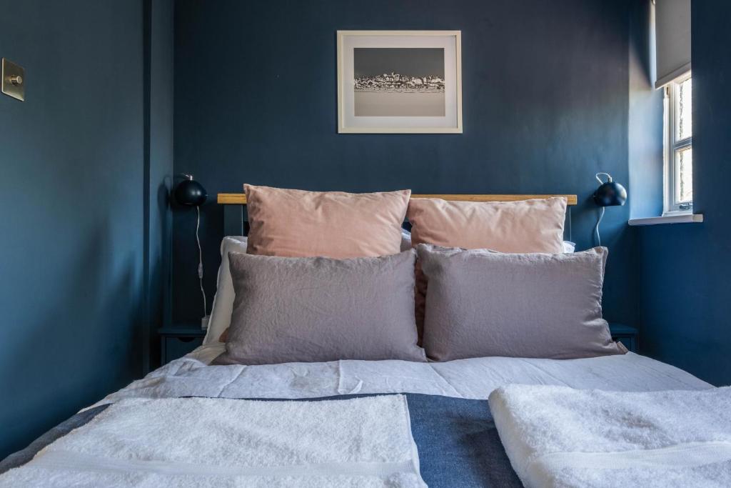 1 dormitorio con paredes azules y 1 cama con almohadas en On the Strand, en Rye