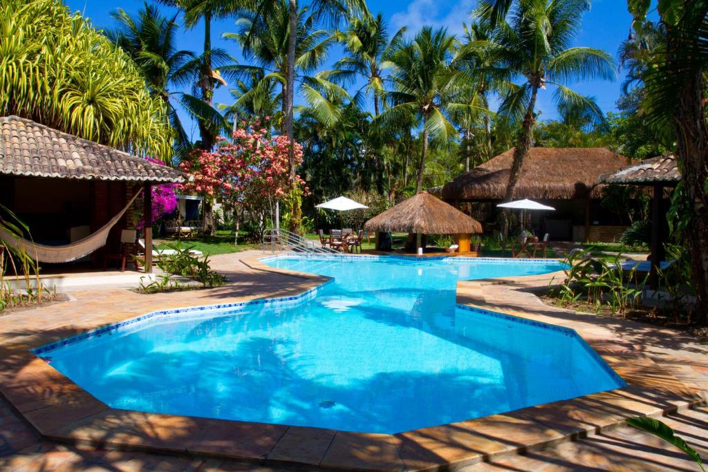 a pool at a resort with palm trees at Pousada Berro do Jeguy in Pipa