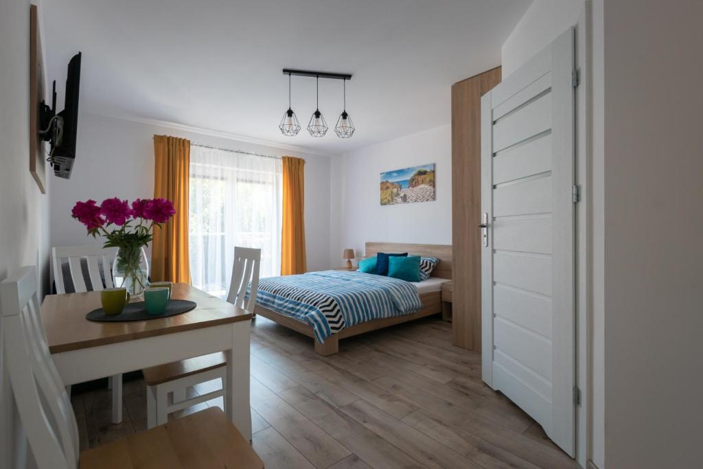 a bedroom with a bed and a desk and a table at Pensjonat Bursztyn in Dąbki