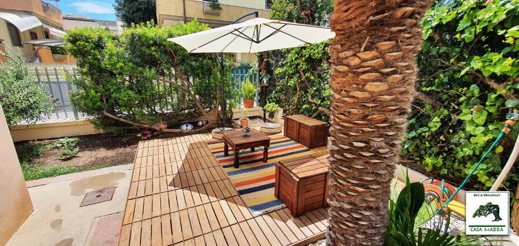 patio ze stołem i parasolem obok drzewa w obiekcie Casa Madda w mieście Selargius