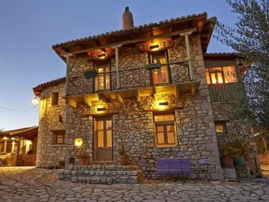 a large stone house with lights on it at Elaion Guesthouse in Elliniko