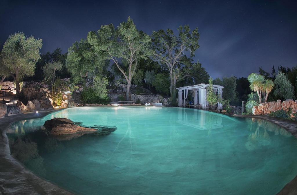 uma grande piscina de água azul à noite em Puntebianche B&B em Ceglie Messapica