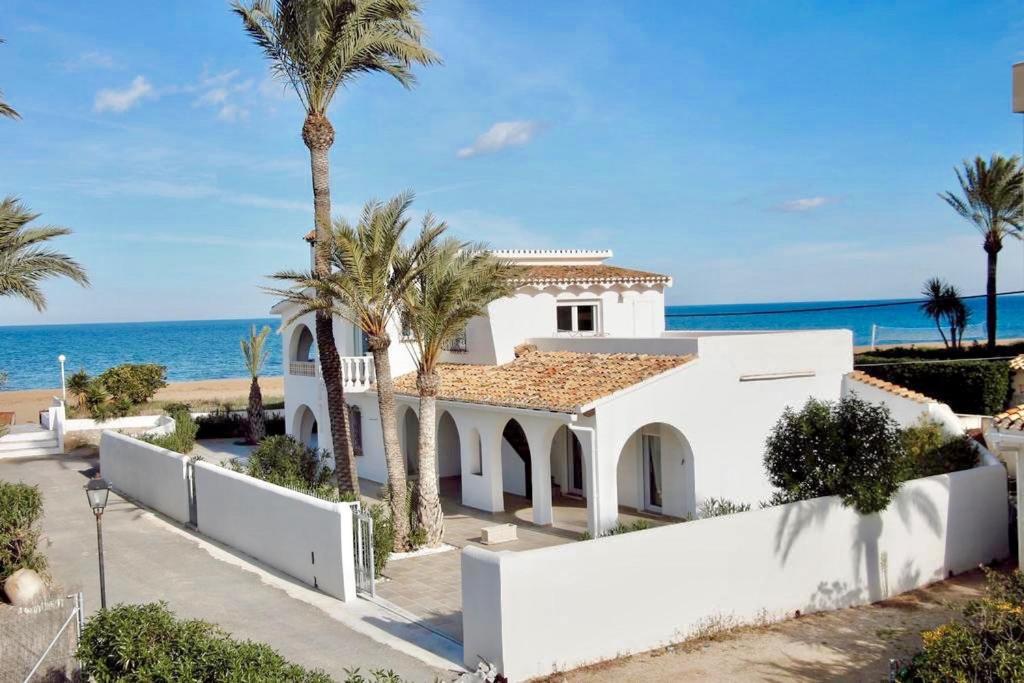 una casa blanca con palmeras y el océano en Urbanización El Oasis, 20 Villas en 1ª Línea Playa, en Denia