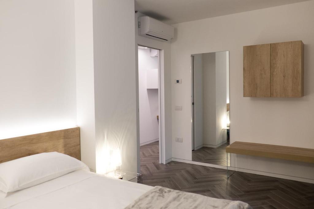 biała sypialnia z łóżkiem i lustrem w obiekcie Terrazze dei Tigli w mieście Riva del Garda
