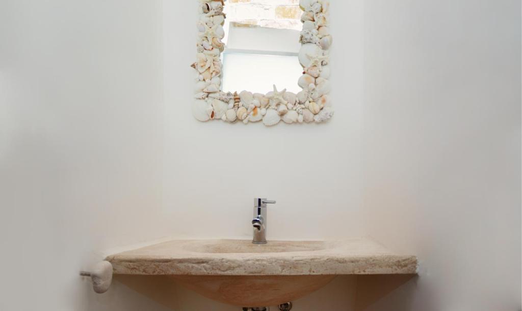 a bathroom with a stone sink and a mirror at Puntebianche B&amp;B in Ceglie Messapica