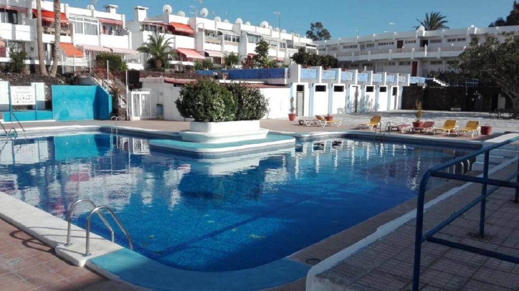 una grande piscina con acqua blu di fronte a un edificio di EL CHAPARRAL Studio-appartement with fantastic pool view and STRONG WIFI a Costa Del Silencio