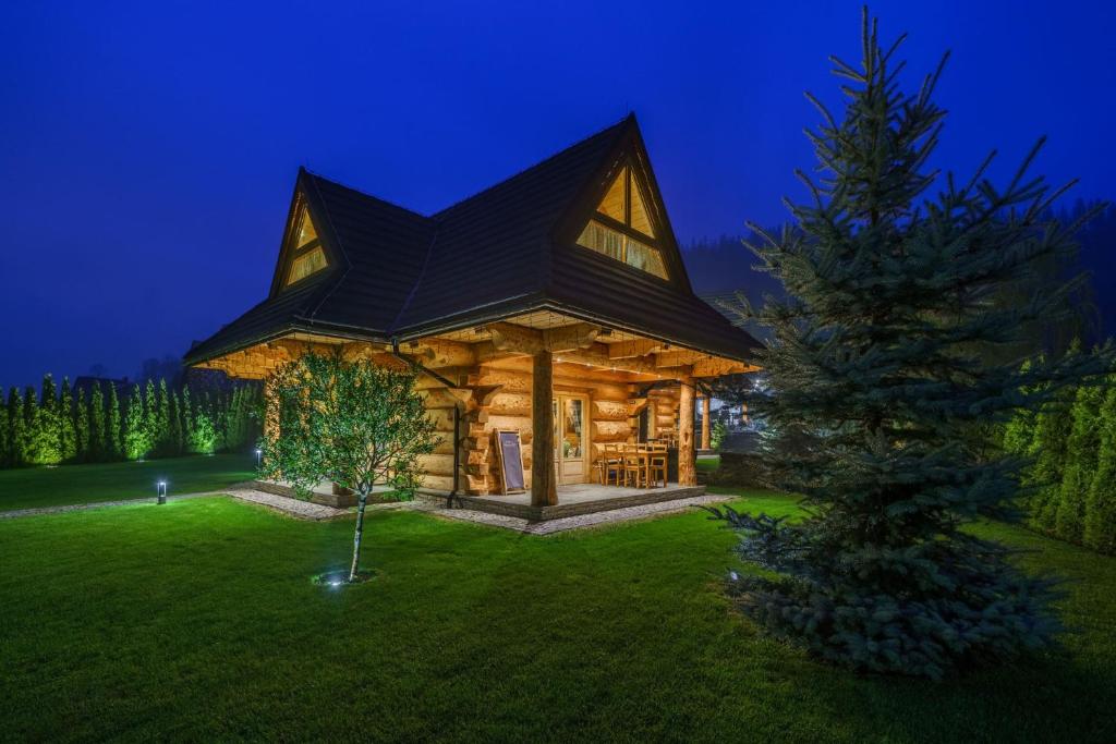 une cabane en rondins avec un arbre de Noël dans la cour dans l'établissement Chalet Wioska Jagny, à Poronin