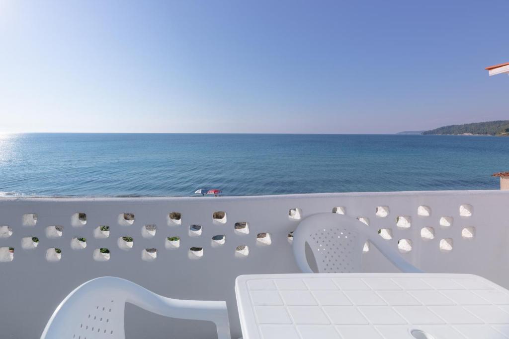 a table and chairs on a balcony overlooking the ocean at Golden sunset beach house in Skala Fourkas