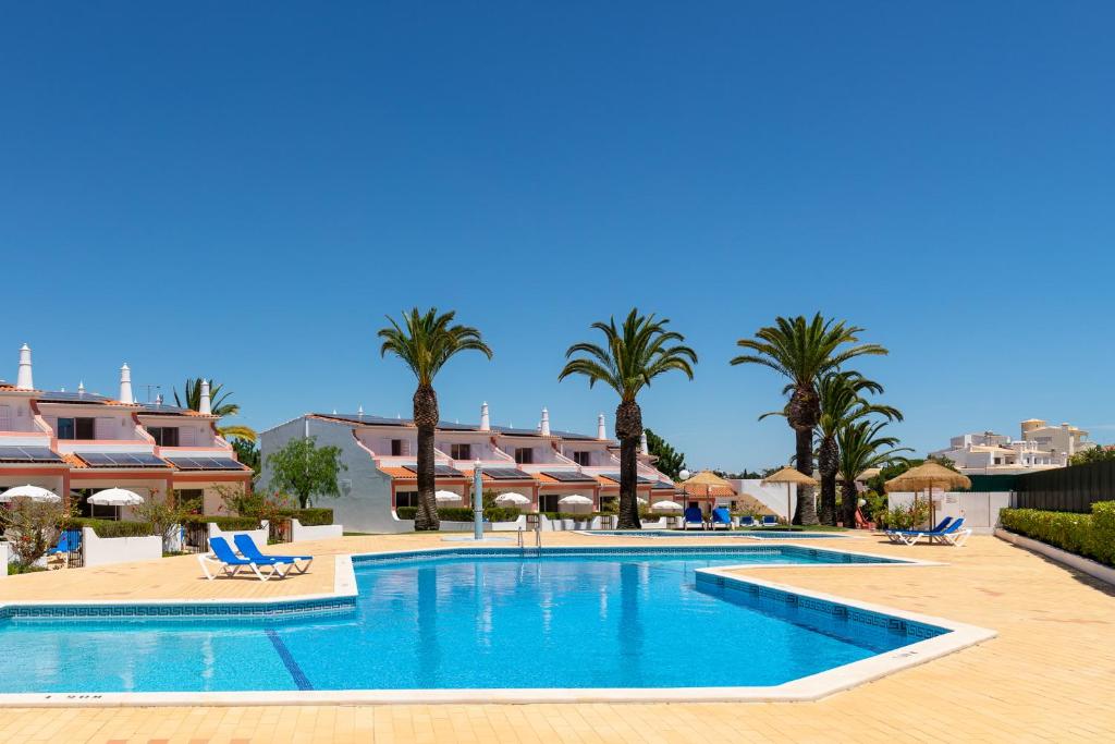 a large swimming pool in a resort with palm trees at Moradias Villas Joinal in Albufeira
