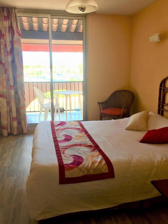 a hotel room with a bed and a large window at Hotel Alhambra in Cap d&#39;Agde