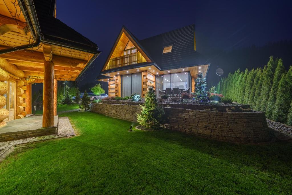 a house with a green yard at night at Luxury Chalet Wioska Jagny in Poronin