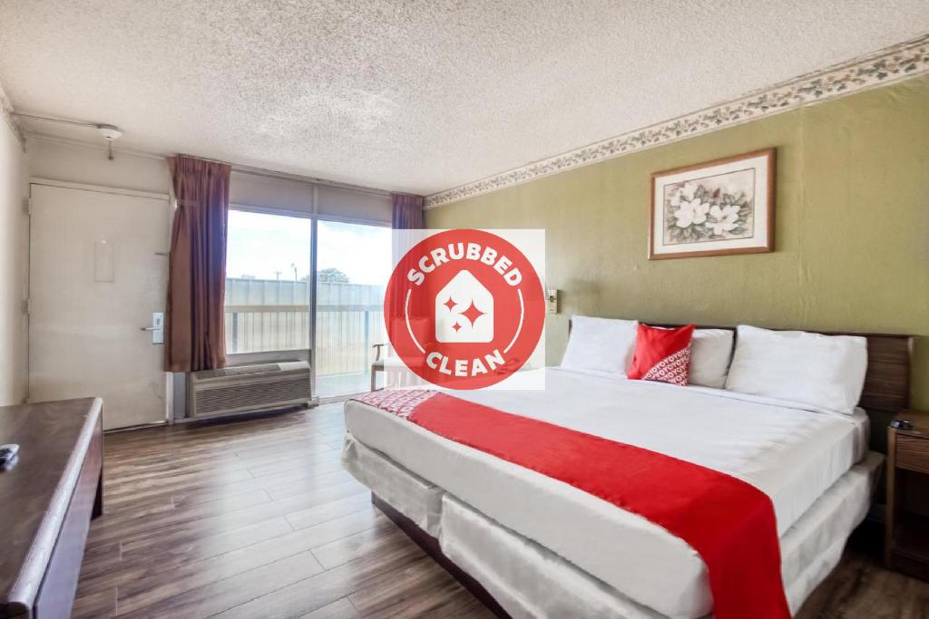 una camera d'albergo con un letto con un cartello rosso sopra di OYO Hotel Brownwood Hwy 67 a Brownwood