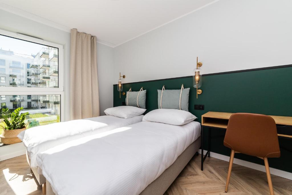 two beds in a room with a desk and a window at Pobookowane Barbary DeLux Old Town in Gdańsk