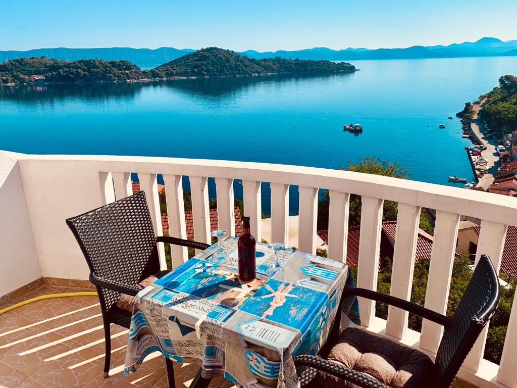 een tafel en stoelen op een balkon met uitzicht op het water bij Guest House Ruža in Sobra