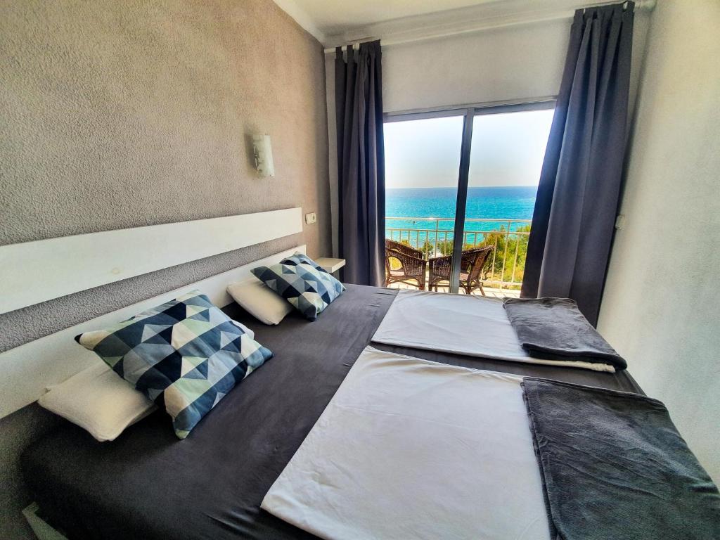 a bedroom with a bed with a view of the ocean at Amena Mar Hotel in Sa Coma