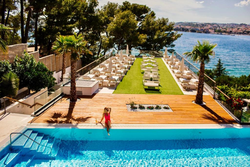 Eine Frau steht in einem Pool in einem Resort. in der Unterkunft Hotel Eden in Podstrana