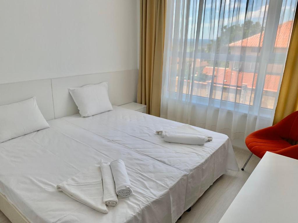 Una cama blanca con toallas y una ventana. en Byala Residence Apartments, en Byala