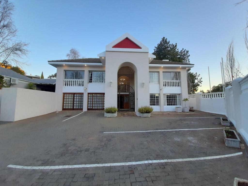 a large white house with a parking lot at Florentia Guest House in Bloemfontein
