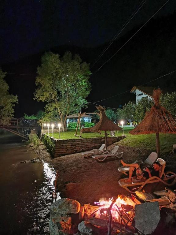 a fire pit with chairs and umbrellas at night at Cabana Carolina in Laz