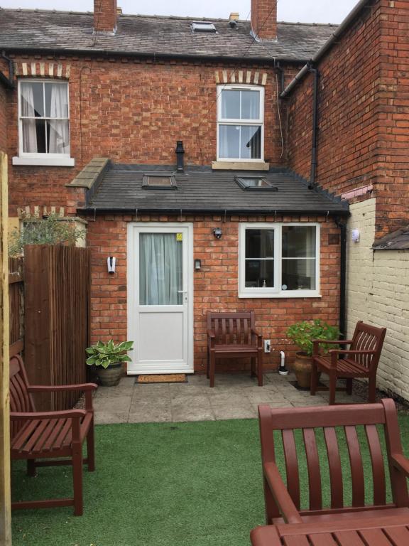 a brick house with two benches and a white door at Primrose in Shrewsbury