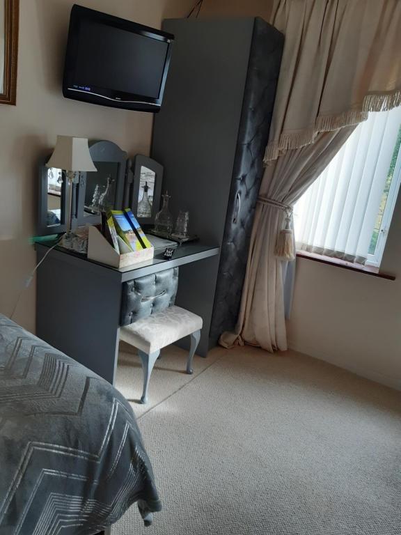 a bedroom with a bed and a desk and a tv at Arch House in Florencecourt