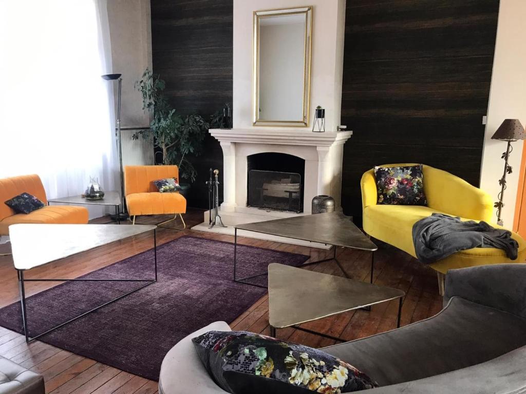 a living room with yellow chairs and a fireplace at A La Villa Perroy les chambres sont spacieuses et les petit-déjeuners offerts in Dunkerque