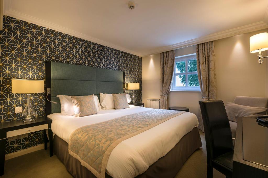 a hotel room with a large bed and a chair at Number Four at Stow in Stow on the Wold