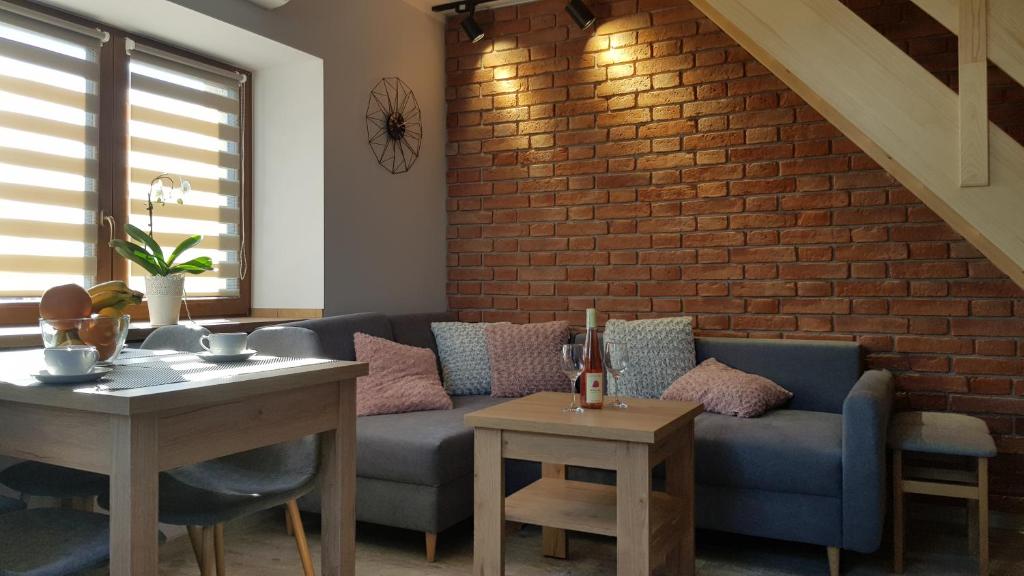 Una sala de estar con un sofá y una pared de ladrillos. en Apartament Komarno III, en Jelenia Góra