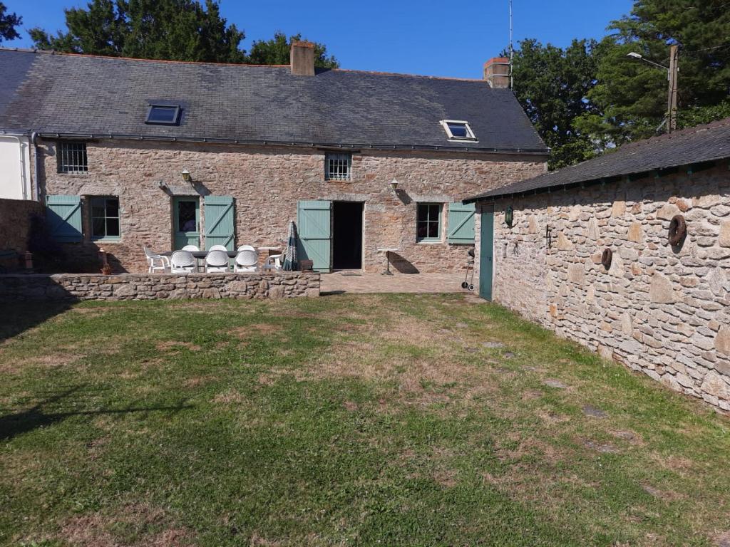 an old stone house with chairs in the yard at Maison briéronne 15 mn de La Baule in Saint-Lyphard