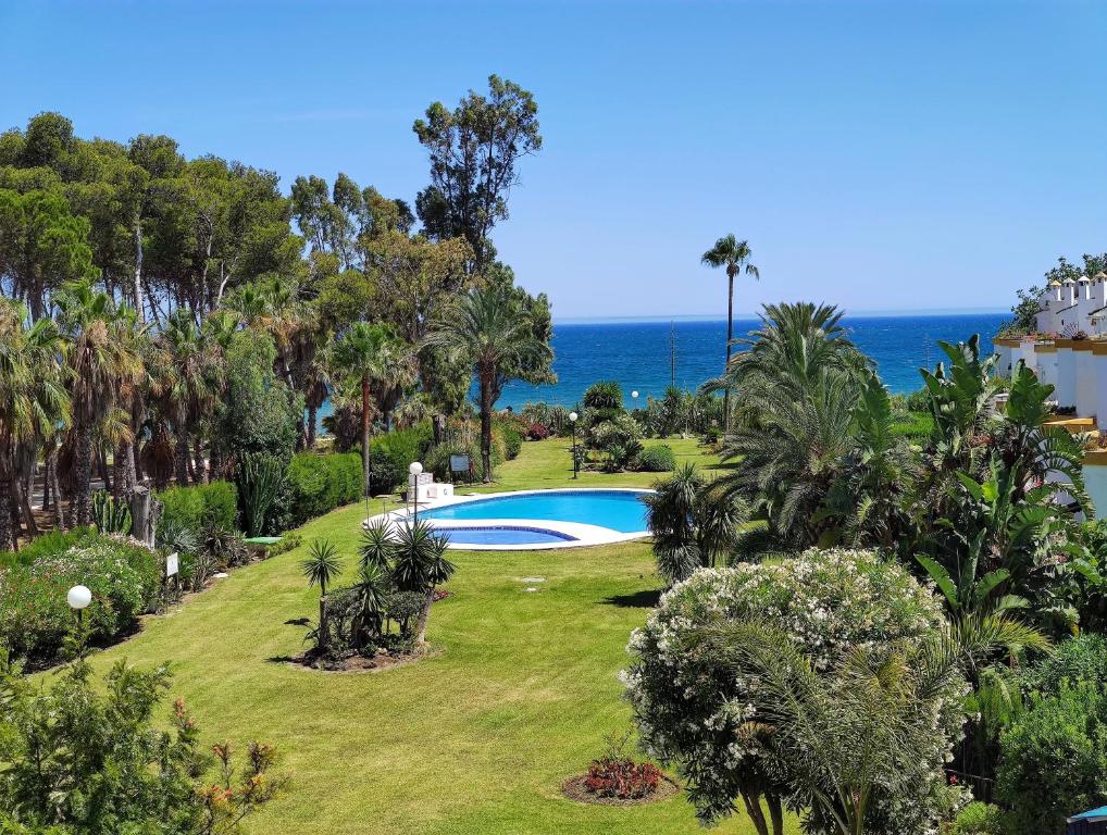 a garden with a swimming pool and the ocean at Spacious Beachfront Town House in Estepona with Fully Equipped Kitchen, Pools, Garden, Sea View in Estepona