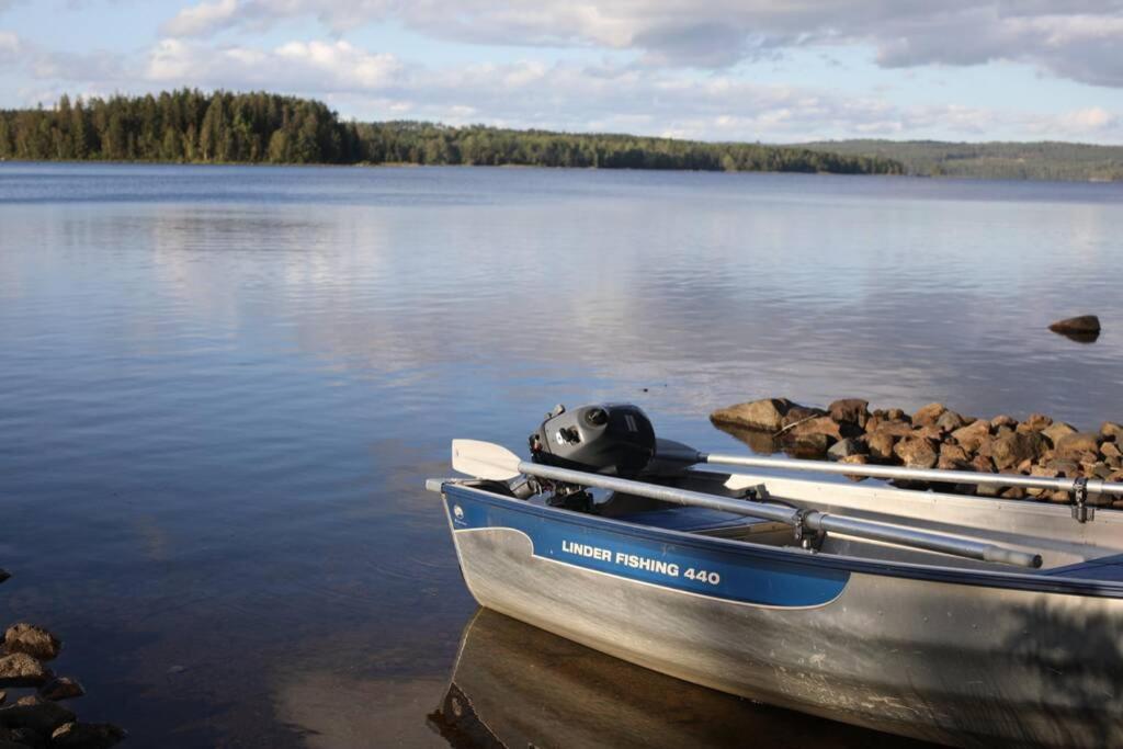 a boat sitting on a lake with two paddles at Sjönära stuga med båt och bastu in Ramkvilla