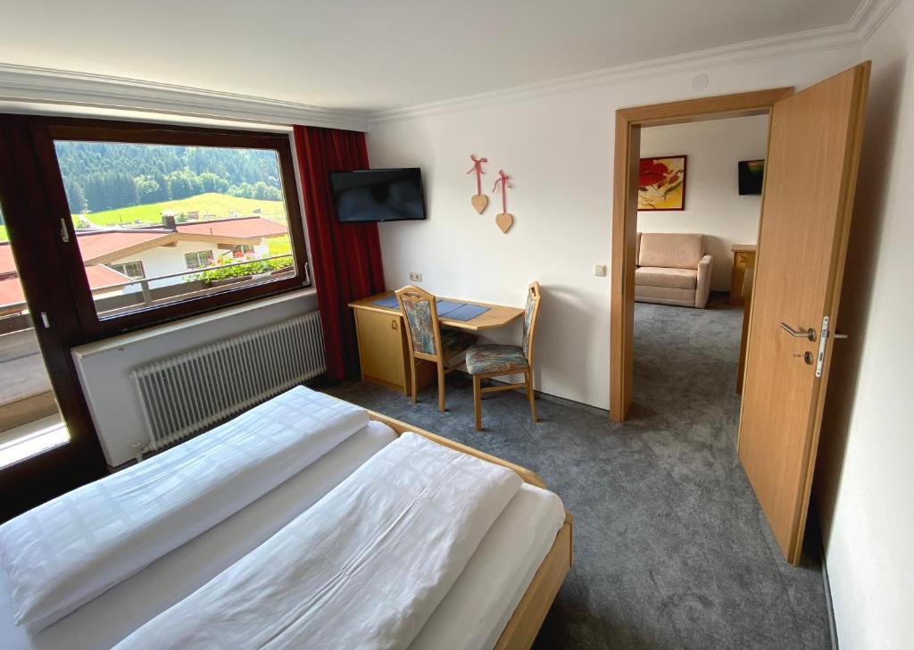 a hotel room with a bed and a desk and a window at Pension Franglhof in Kirchberg in Tirol