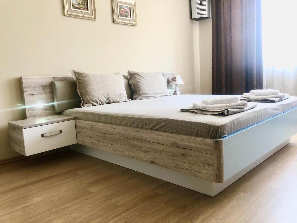 a bedroom with a large bed with a wooden floor at Апартаменти Корал in Kiten