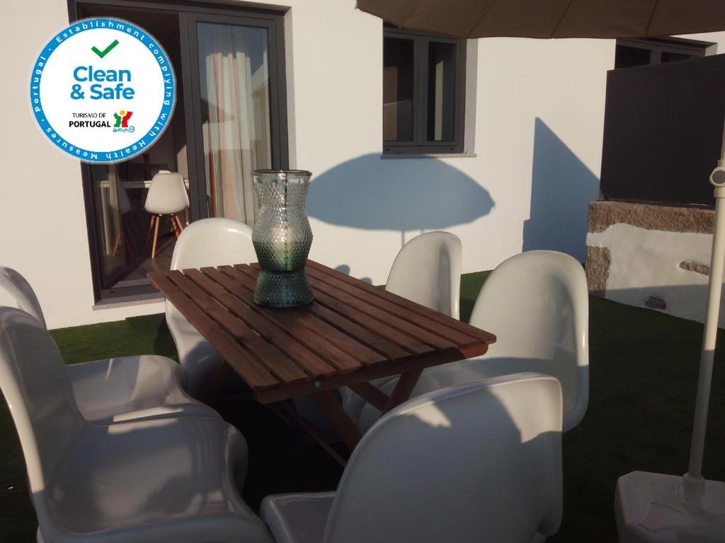 a vase sitting on a wooden table with white chairs at Casas do Pedro T3 in Vila Praia de Âncora