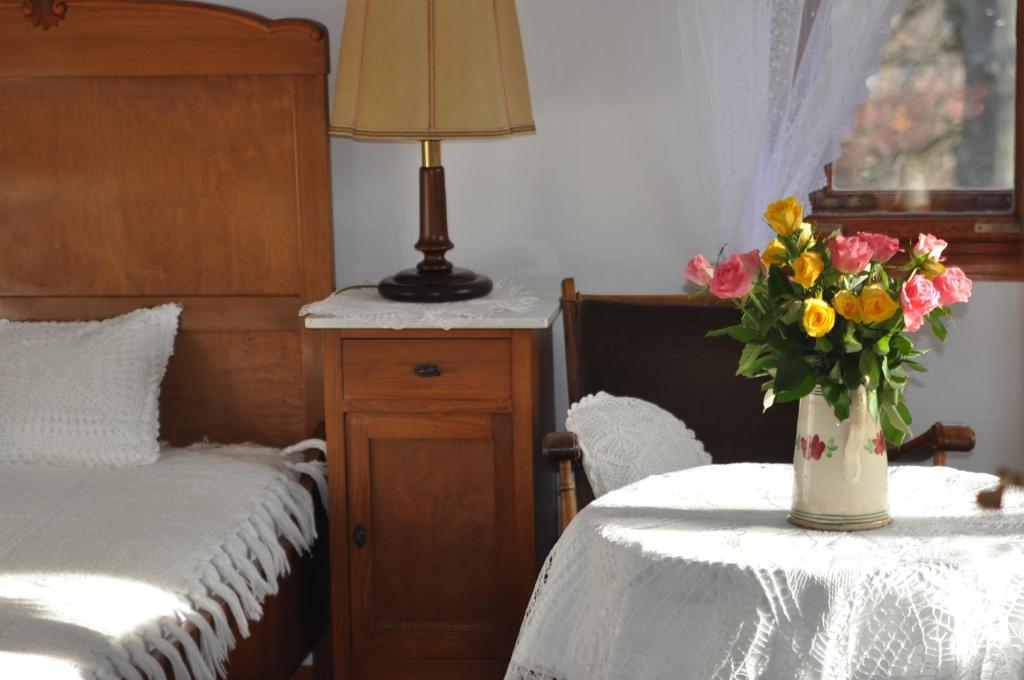 een slaapkamer met een bed en een vaas met bloemen op een tafel bij Villa Nostalgia in Szklarska Poręba