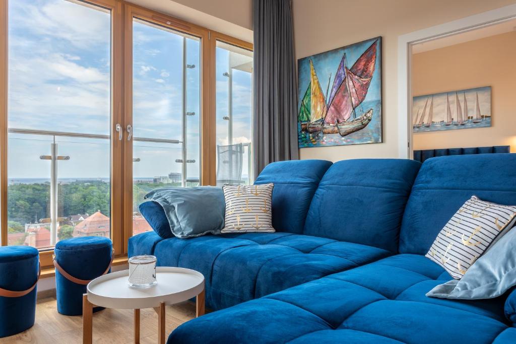 niebieską kanapę w salonie z dużym oknem w obiekcie Ambria Apartments Platan Tower w Świnoujściu