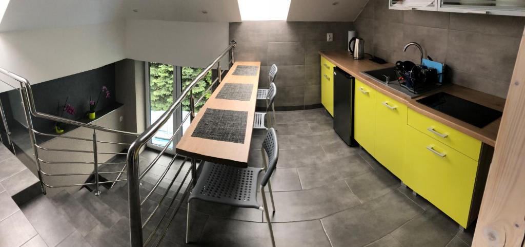 a kitchen with yellow cabinets and a table with chairs at Noclegi u Alicji in Wola Kalinowska