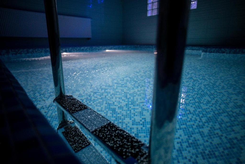 姆龍戈沃的住宿－Hotel Rezydencja Mazury SPA & Lake，游泳池铺有蓝色瓷砖地板,水面