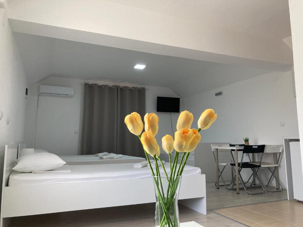 a vase with yellow flowers in a bedroom at TIKI Apartments in Gevgelija